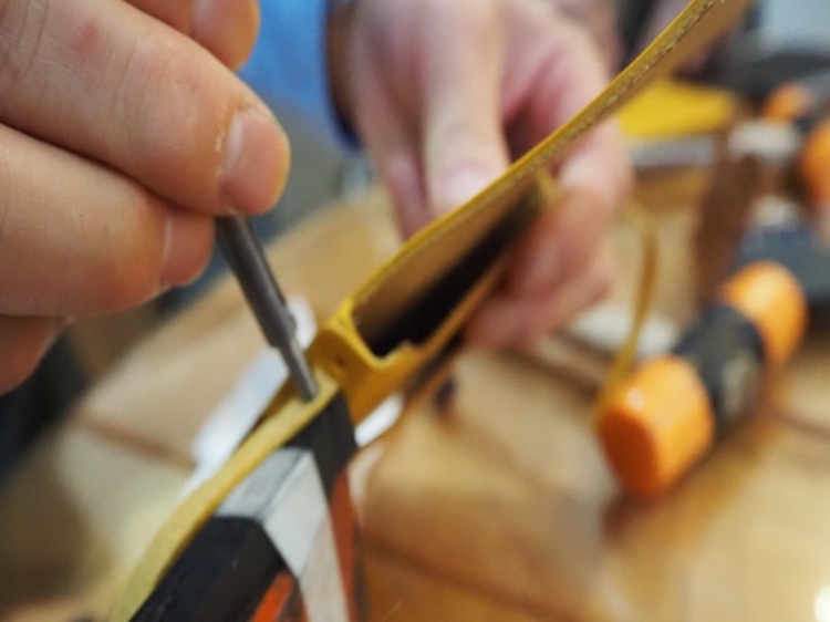 制作中のスマホショルダーに金具を付ける様子   