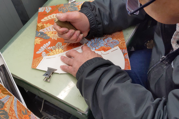 廃棄された着物を靴の形に裁断する型抜きの工程